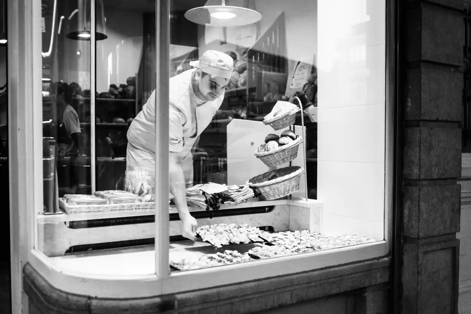 Boulanger garnissant la vitrine de la boutique